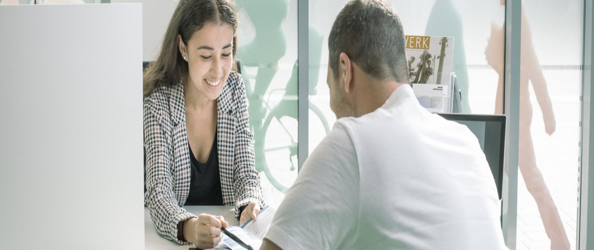 eine Auszubildende sitzt im ServiceCenter im Kundengespräch und erklärt die Preisliste